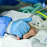 TOPSHOT - A member of the medical staff comforts and holds the hand of a patient infected by the novel coronavirus at the COVID-19 division at the ASST Papa Giovanni XXIII hospital in Bergamo, on April 3, 2020. - Italy's three-week lockdown to stop the spread of COVID-19 has been extended through at least mid-April and its economy is expected to suffer its biggest peacetime shock since World War II. (Photo by Piero CRUCIATTI / AFP) (Photo by PIERO CRUCIATTI/AFP via Getty Images)